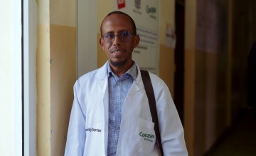 Man wearing white jacket with Concern logo standing in a doorway