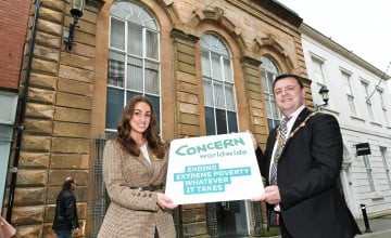 A woman and man holding a board outside an historic building