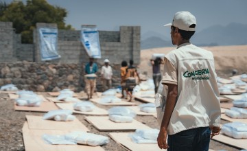 A man stands overlooking rows of materials used to make shelters