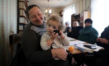 A woman and her daughter in a room with other people
