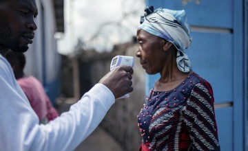 A staff member of the CBCA Virunga Hospital checks a visitor's temperature using a contactless infrared thermometer, before allowing her access to the hospital in Goma, DRC