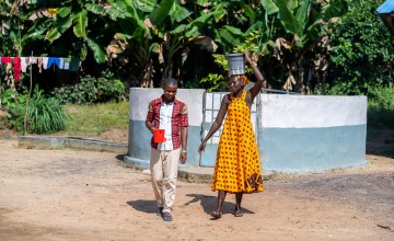 A man and woman collect water from a village water pump