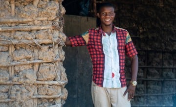 A young man standing in a doorway smiling