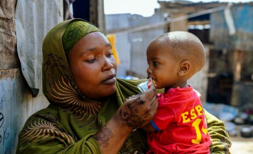 A woman in a displacement camp holding a young boy in her arms