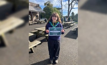 A young woman in a Scout uniform holding a certificate