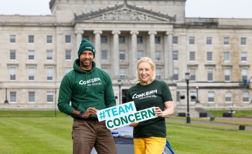 A man and woman holding a sign while standing outside Stormont in Belfast