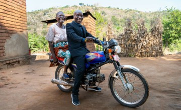 Hariet and Alani with their motorcycle they purchased with money from Concern. Their main work is farming and they run a grocery shop. Photo: Chris Gagnon/Concern Worldwide.