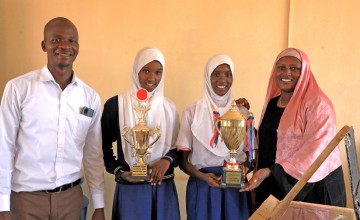 Two young women holding trophies with their teachers standing beside them