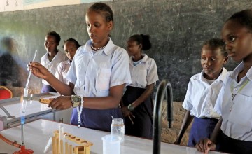 A young woman student uses a science kit in her classroom with other girl pupils