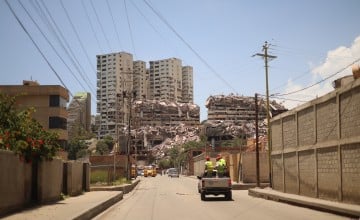 A car drives towards destroyed buildings in Venezuela