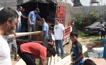 Concern employees organising the distribution of new tent kits (including wood, plastic sheeting etc) to families whose homes were recently burnt down. The tents are going to be built on this field in Northern Lebanon. Photograph by Mary Turner/Panos Pict