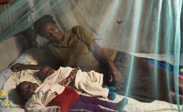 Florence Mutungi with six-month-old twin daughters Blessings and Precious. The family’s Community Health Volunteer has encouraged them to use the mosquito net provided when the girls were born to protect them against malaria. Photo: Peter Caton