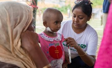 Concern's Asfia Azim measures the upper arm circumference of two year old Lukia* at the nutrition center at Moynadhona refugee camp for Rohingya in Cox's Bazar, Bangladesh.