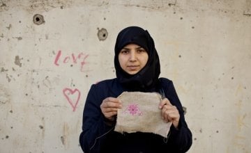 Layal, 27 a refugee from Syria, holding her embroidery as part of a programme to reduce tensions and earn some income through embroidery. Photo by Abbie Trayler-Smith/Panos, Lebanon 2016