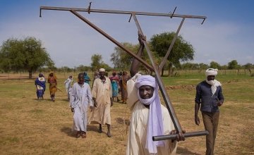 Osman Zakaria carries a planting tool to the conservation agriculture demonstration plot at Ridjil Dour village in Chad.
