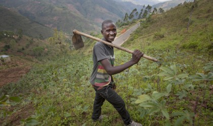 Gerard Ndabahekeye (28) with his new hoe bought with the profits of his business, a small shop, which he was able to set up due to the investment of the Graduation Programme. Photographed in his cassava field near his home in Bukinanyana, Cibitoke, Burundi. Photo: Abbie Trayler-Smith / Concern Worldwide