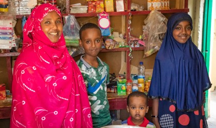 Zeinab, piactured with her children, stand in their grocery shop in Arabsiyo, which was set up with support from Concern. Photo: Gavin Douglas / Concern Worldwide / Somalia