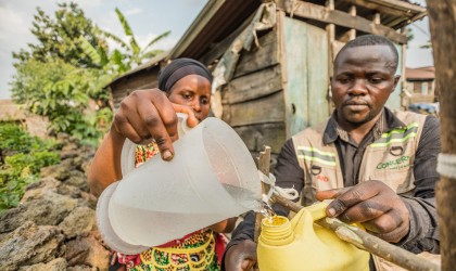 Apoline Niyosenge is taught how to wash her hands properly by Concern community worker Abel Bamwisho, after having installed the handwashing station in front of her latrine, Kitshanga. Photo: Pamela Tulizo/Panos/Concern Worldwide