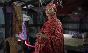 A pregnant woman in Bangladesh stands with her hands on her stomach