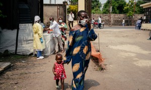 A woman wearing a mask as a preventive measure enters Kyeshero Hospital after passing a checkpoint for hand washing and health screening in Goma