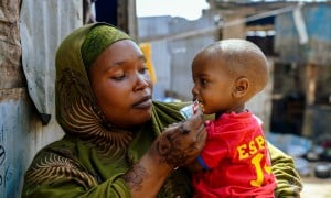 A woman in a displacement camp holding a young boy in her arms