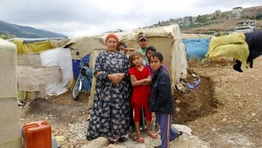 Arwa with her grandchildren in front of her makeshift shelter in an informal tented settlement near the Syrian border.