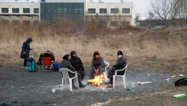 People sitting around small fire at Polish border