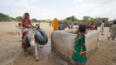 Woman and children collecting water at a well