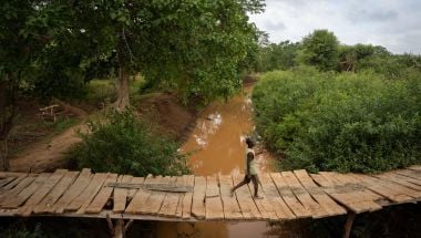 A man uses a small bridge to cross a river in Mikemani village, Tana River County. Photo: Zurich Flood Resilience Alliance/Concern Worldwide