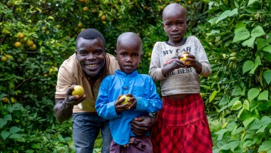 Father stands with two children on their farm, holding lemons