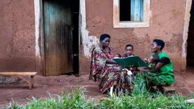 Two women and their children outside a house.