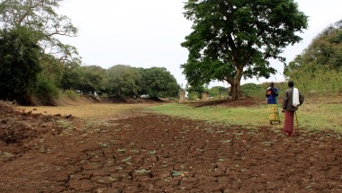 Two people stand next to a dry river bed