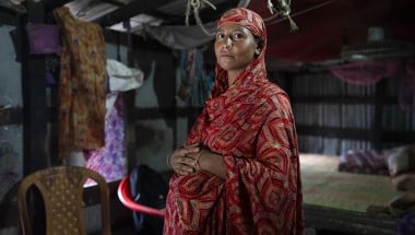 A pregnant woman in Bangladesh stands with her hands on her stomach