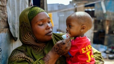 A woman in a displacement camp holding a young boy in her arms