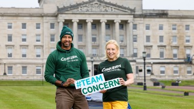 A man and woman holding a sign while standing outside Stormont in Belfast