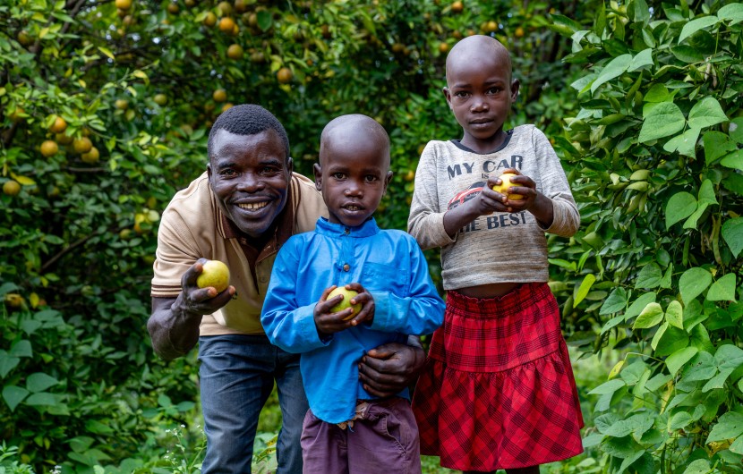Father stands with two children on their farm, holding lemons