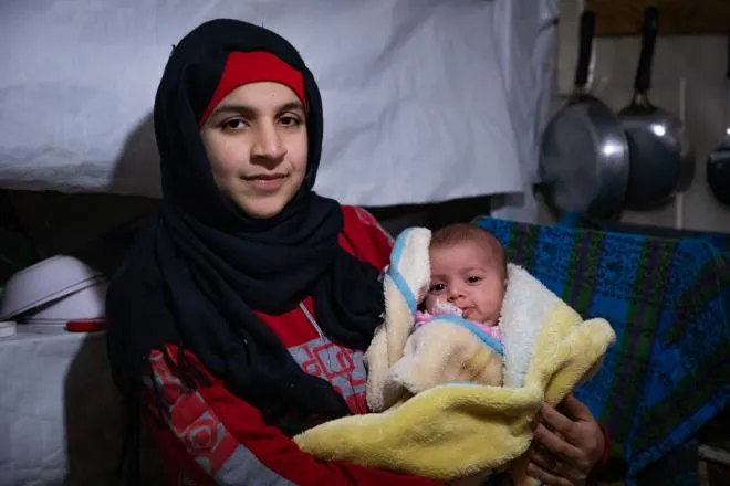 Wafdeh* (20) with heryoungest daughter Rajaa* (2 months) in the makeshift kitchen. Concern provide this family with blankets and other materials to make the harsh winter a little more bearably.  Photo: Gavin Douglas/ Concern Worldwide
