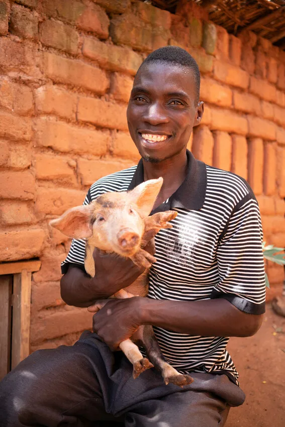 Aubrey with one of his sow’s piglets in Malawi. Photo: Chris Gagnon / Concern Worldwide