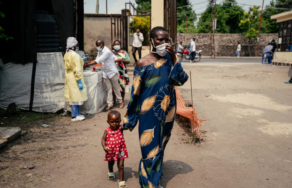 A woman wearing a mask as a preventive measure enters Kyeshero Hospital after passing a checkpoint for hand washing and health screening in Goma