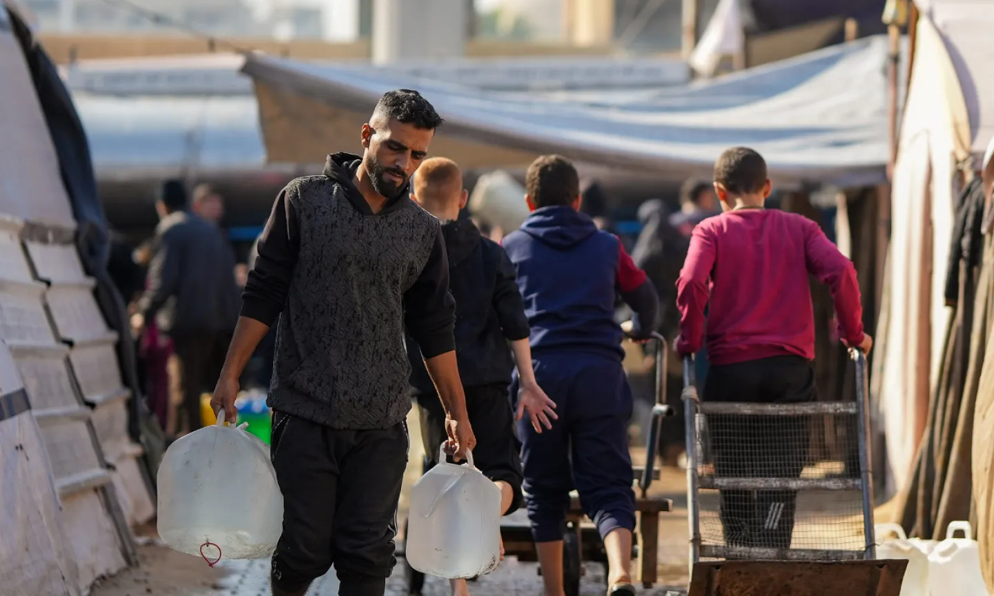 A man carrying water containers in a displacement camp