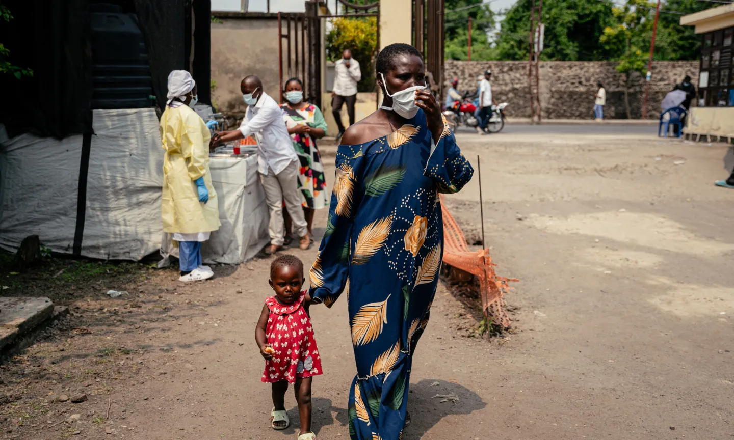 A woman wearing a mask as a preventive measure enters Kyeshero Hospital after passing a checkpoint for hand washing and health screening in Goma