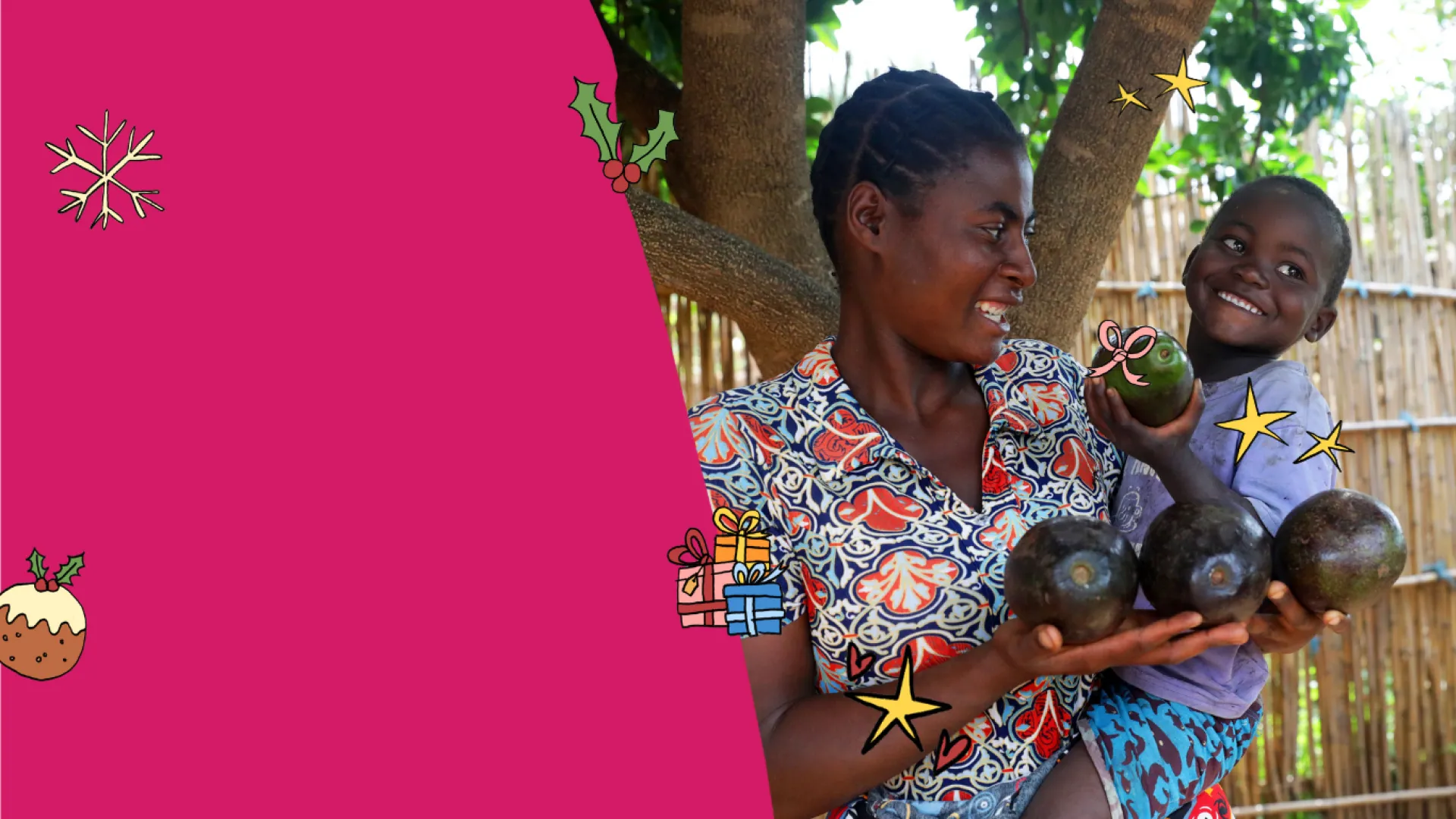 A smiling woman holds several avocados in her hands while carrying a young child, who happily holds up another avocado. They stand under a tree beside a wooden fence.