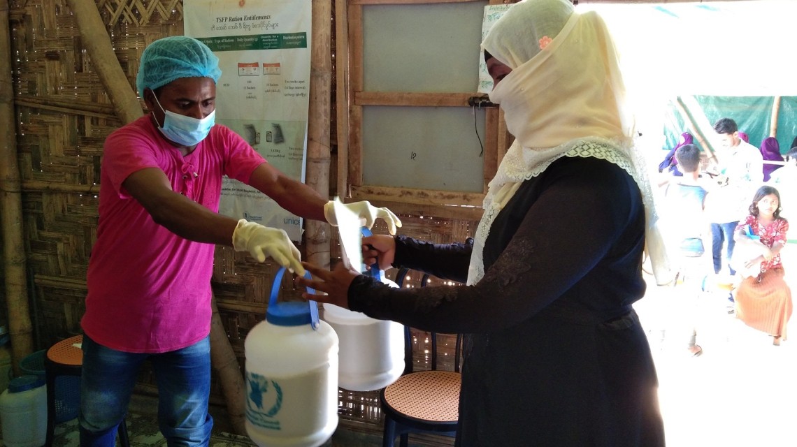Uzair*, Rohingya Volunteer, helping Concern on double distribution to programme participants. Photo: AKM Jakaria