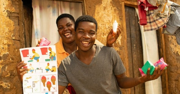 Patricia Moloko with her son George pictured with the soap and Covid-19 fliers they have received from Concern Malawi.