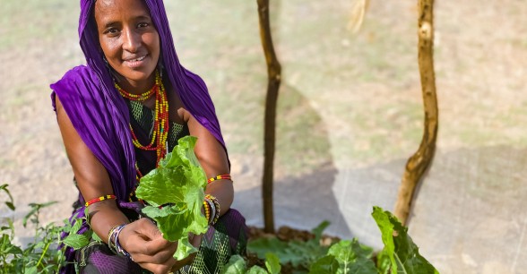 Sori in her kitchen garden in Kalacha, Marsabit. She is holding some of the vegetables she has been able to grow in her kitchen garden in the Chalbi desert. Photo: Jennifer Nolan / Concern Worldwide