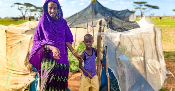 Sori with her son Abudho in Kalacha, Marsabit, standing outside their kitchen garden full surrounded by desert. This season the harvest will include butternut squash, watermelon and spinach. Photo: Jennifer Nolan / Concern Worldwide