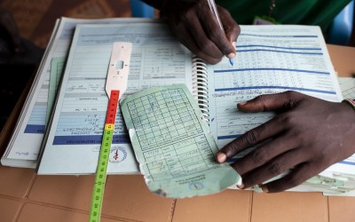 The programme assistant records details of patient visits at a nutrition clinic run by Concern Worldwide in a POC in Juba, South Sudan. Photo: Abbie Trayler-Smith / Concern Worldwide