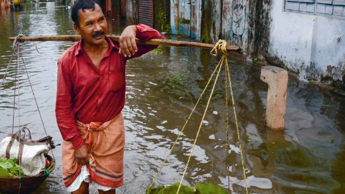 An Indian vegetable vendor carries his wares through floodwaters in Siliguri, West Bengal, on July 24, 2016. AFP/Diptendu Dutta 2016.