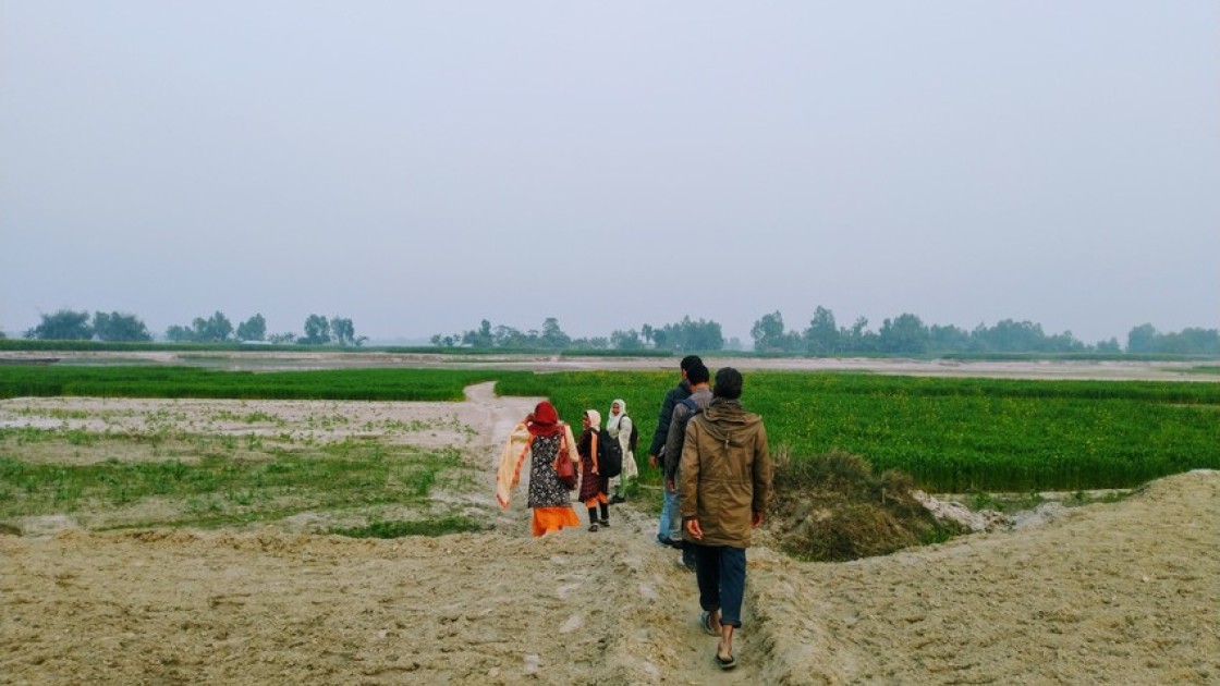 Community members from Dakhin Dawabari Char of Dawabari Union, Hatibanda, Bangladesh show the way to reach their community on the hour long walk across the sand of the dried river bed during dry season. In monsoon season, the river swells, filling all the area covered in sand in this photo, completely isolating this community. Photo: Amy Rose McGovern / Concern Worldwide