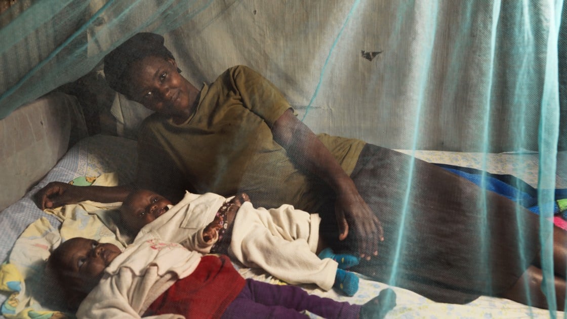 Florence Mutungi with six-month-old twin daughters Blessings and Precious. The family’s Community Health Volunteer has encouraged them to use the mosquito net provided when the girls were born to protect them against malaria. Photo: Peter Caton